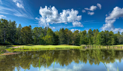 A green golf course with a cloudy blue sky on a beautiful summer day in Canada