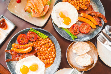 Top view of English breakfast menu fried eggs baked beans in tomato sauce and bacon sausage in plate