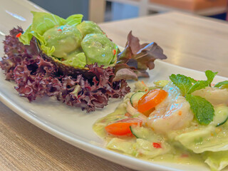 Beautifully arranged plate featuring a refreshing and vibrant juicy shrimp salad, served on a sleek white plate against a wooden table backdrop.