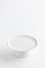 Empty tableware - white plate cakestand on white table as a background for a dessert vertical photo with a copy space, food mokup