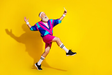 Full length photo of cheerful positive mature guy dressed retro sport jacket tacking selfie modern device emtpy space isolated yellow color background