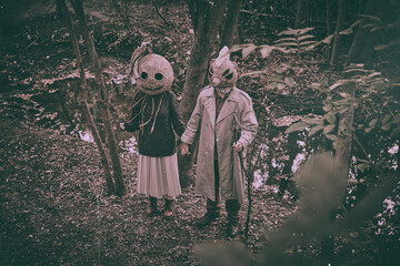 Haunting, terrifying people standing in deep forest, wearing creepy masks and odd clothes, holding...