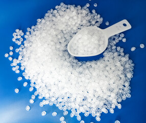 virgin raw material granules, white plastic resin material granules hot cut type, isolated on blue...