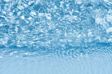 Blue water with ripples on the surface. Defocus blurred transparent blue colored clear calm water surface texture with splashes and bubbles. Water waves with shining pattern texture background.