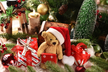 Christmas arrangement with teddy bear in Santa hat sitting with gift boxes
