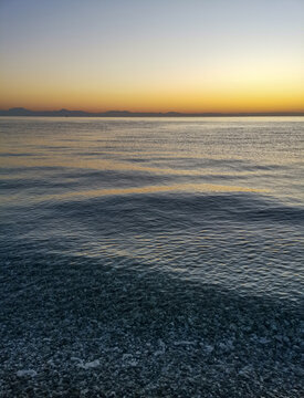The ocean is calm and the sky is orange