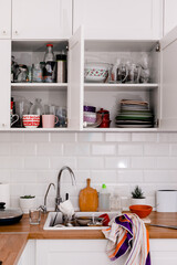 Clutter, dirty dishes by the sink in the white kitchen