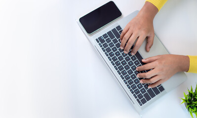 Office desk clean and minimal working scene with businesswoman hands over a silver laptop keyboard on a white office table in workplace, Top view, Copy space.