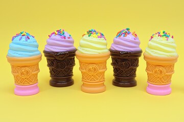 Colorful ice cream cones with sprinkles against a bright yellow background, perfect for summer treats and dessert themes.