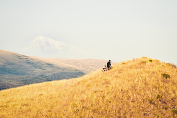 Fit young caucasian male person push bicycle uphill with mountains background outdoors in caucasus...