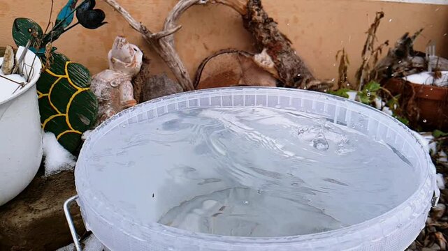 Video von Wassertropfen in Echtzeit und Slow Motion die in einen Eimer fallen