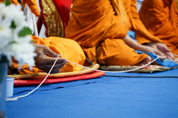 Selective focus on the hand of Buddhist holding the white rope while praying