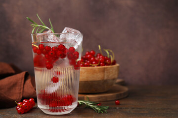 Refreshing water with red currants and rosemary in glass on wooden table, space for text