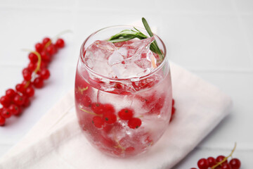 Refreshing water with red currants and rosemary in glass on white table, closeup