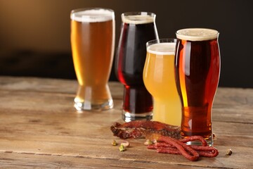 Glasses with different types of beer and snacks on wooden table