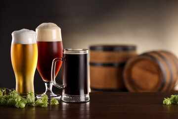 Glasses with different types of beer and fresh hops on wooden table in bar. Space for text
