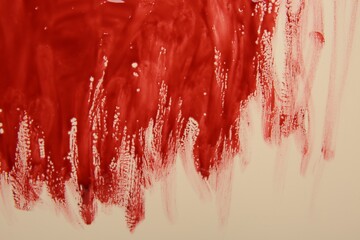 Red blood on beige background, top view