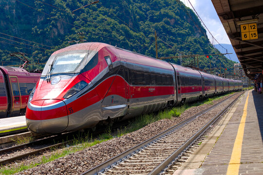 Red and silver colored high speed train named Frecciarossa arriving at railway station of Italian City of Bozen on a sunny summer day. Photo taken July 17th, 2024, Bolzano Bozen, Italy.