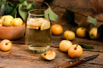 Apple compote in a glass on a wooden table with a background of fresh yellow apples. Cool summer apple drink with your own hands. Preserves for the winter, diet