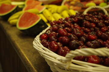 Diferentes frutas con cesta de cerezas en primer plano, detalle de surtido de fruta en un mercado,...