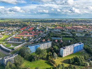 Aerial drone image of construction scaffold renovation of flat appartment building with new houses with red tiled roof and solar pv panels in Sneek, the netherlands