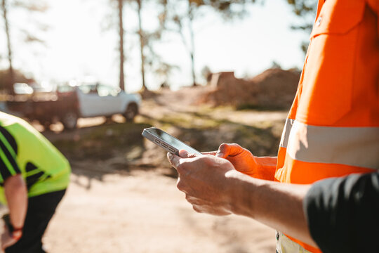 Construction worker holding a mobile device at the construction site.