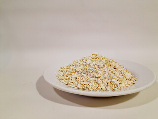 oat, oat grains, oat flakes in a white plate, isolated on white background and close up shot.