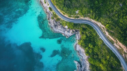 Aerial view of a winding coastal road bordered by vibrant greenery and clear blue waters highlighting a stunning landscape ideal for travel and exploration
