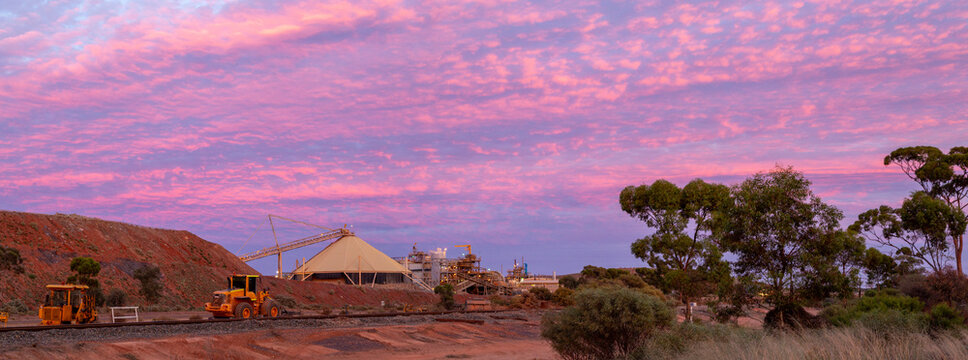Sunset panorama of mine site and heavy machinery.