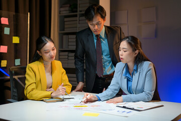 Three women and a man are sitting at a table with papers and a whiteboard