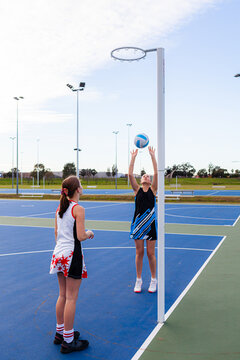 Teenaged aboriginal netball player shooting a goal on the court