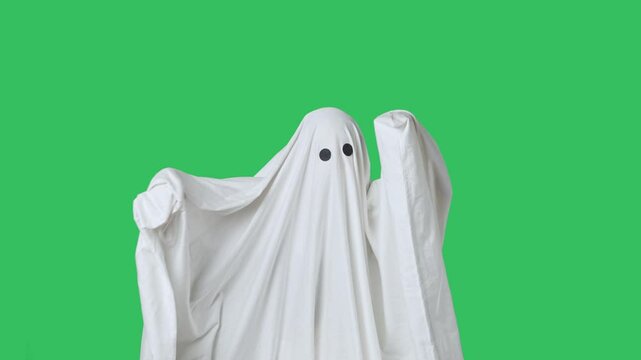 Funny halloween ghost in white sheet dancing cool trendy dance, having fun, isolated on chroma key green screen background. Happy halloween spooky concept.