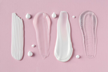 Smears of different cosmetic products on pink background, flat lay