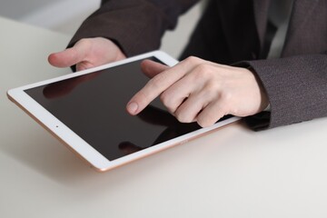 Businessman using tablet at white table indoors, closeup. Modern technology