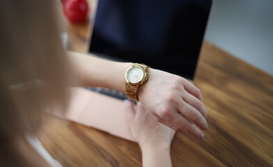 Obraz premium Close-up of office worker woman look at time on wristwatch and wait end of shift. Female late and check time, in rush home. Job, accessory, timing concept