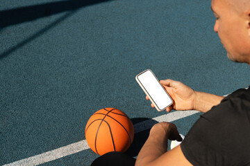 Basketball player using smartphone and social media during game interval. Sports mock up. View from above.