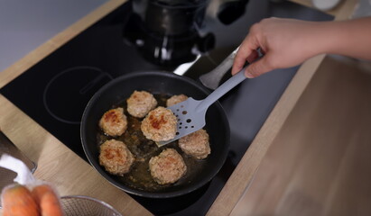 Top view of meat balls beginning to fry in oil in frying pan on kitchen stove. Housewife cooking...