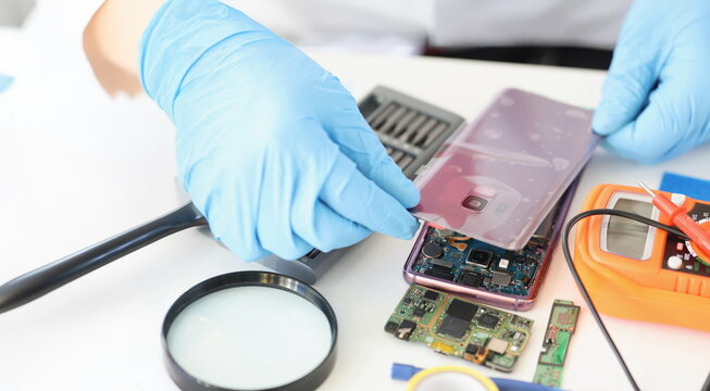Close-up of male put back panel on mobile phone cover wire connections. Person worker in gloves repair modern device. Repair service, quick help concept