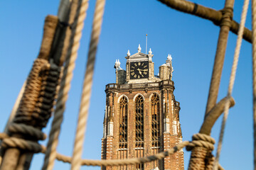 The majestic Dordrecht Cathedral is framed through the intricate rigging of an old galleon ship,...