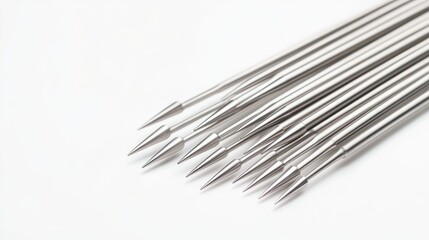 A collection of shiny metal needles arranged neatly on a white background, perfect for sewing and crafting projects.