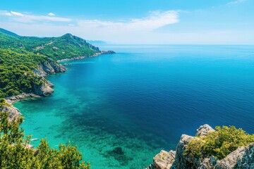 Obraz premium Breathtaking coastal view with clear blue water and lush green hills.