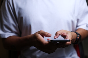 Male hands using a smartphone or tablet in a room. Holding hands. Black background. Home office. For work. for social media or looking for information.