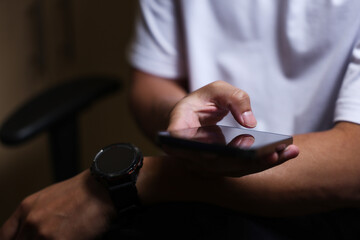 Male hands using a smartphone or tablet in a room. Holding hands. Black background. Home office. For work. for social media or looking for information.