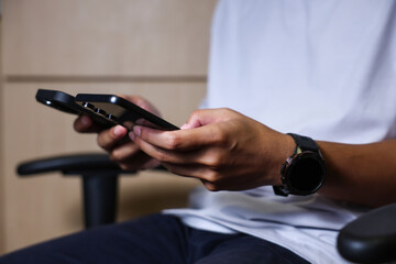 Male hands using a smartphone or tablet in a room. Holding hands. Black background. Home office. For work. for social media or looking for information.