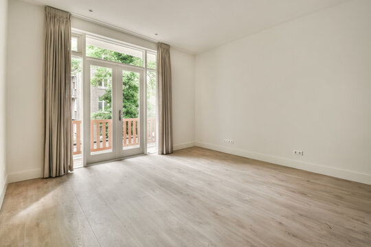 Spacious empty room with balcony doors and hardwood floor