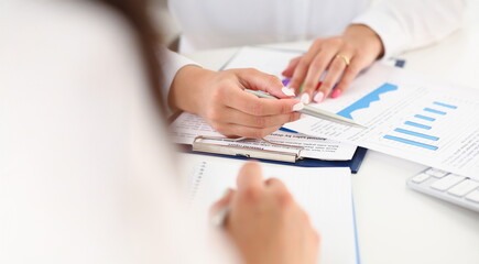 Close-up of female workers discussing working moments and check financial report. Workplace with mess of documents. Business, economy, investment concept