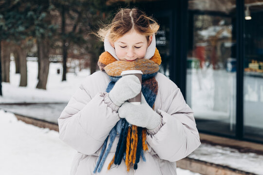 Young girl enjoying a cozy drink during a snowy walk