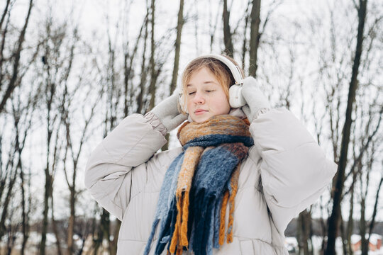 Teenage girl enjoying music on a snowy winter day