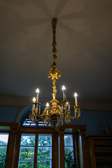 Electric gilded chandelier suspended and lit.
