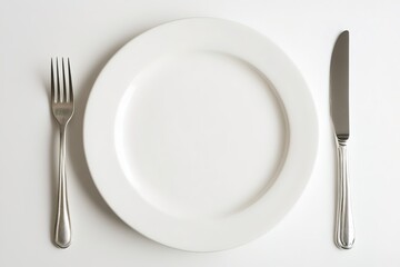White plate with silver fork and knife on table